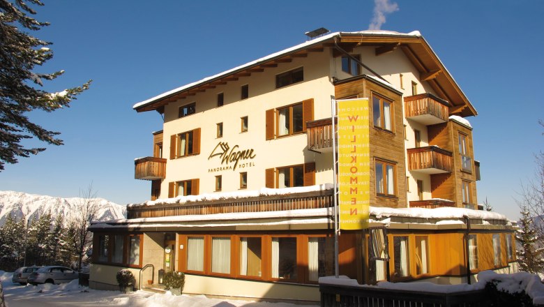 A hotel in the snow with balconies and blue sky in the background.