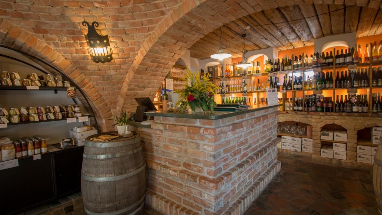 Cozy wine bar with brick walls, shelves full of wine bottles and a rustic counter.