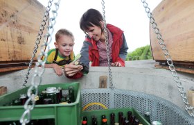 A child and a woman look at bottles in a fountain.