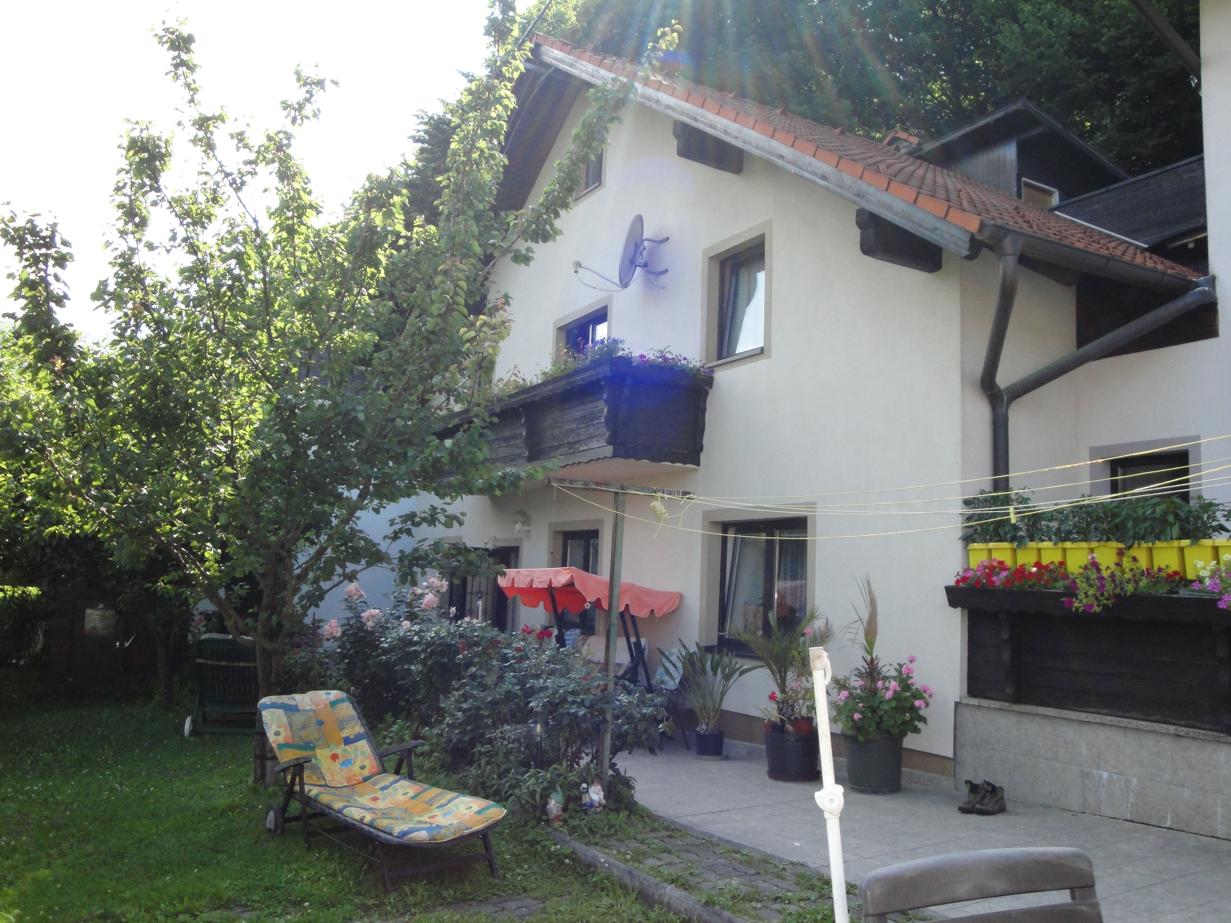 A house with a garden, deckchairs and flowers on the terrace.
