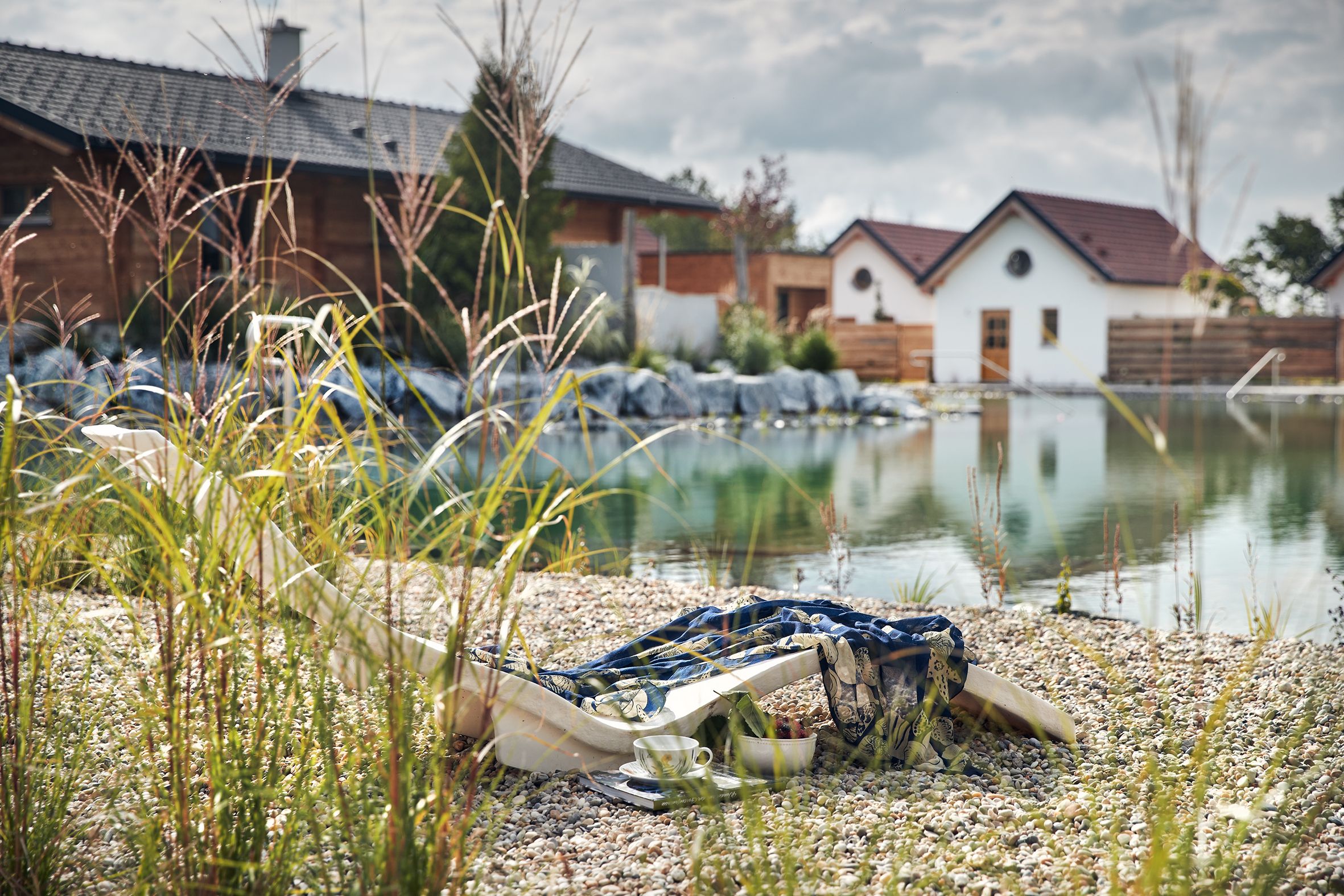 Aerial view of chalets on the garden lake with jetty and deckchair.