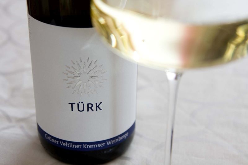 Wine bottle with label 'TÜRK' and wine glass with white wine.