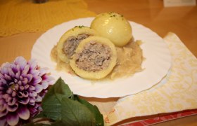 A plate of Waldviertel meat dumplings on sauerkraut, decorated with a flower.