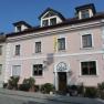 Exterior view of a pink house with white window frames and a yellow flag.