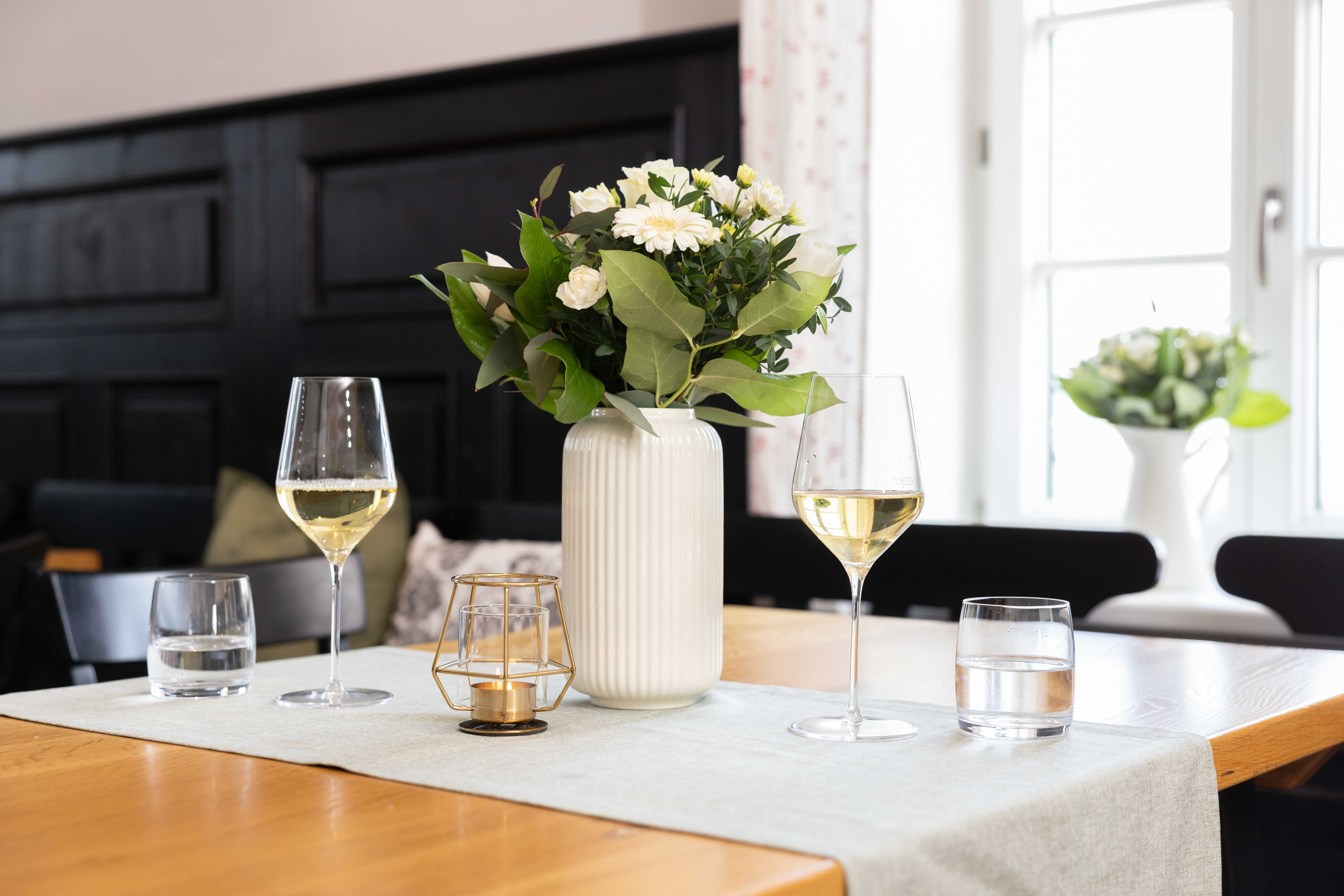 Table with two wine glasses, vase and candle