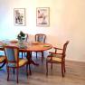 Dining room with oval wooden table, six chairs, two murals and decorations.
