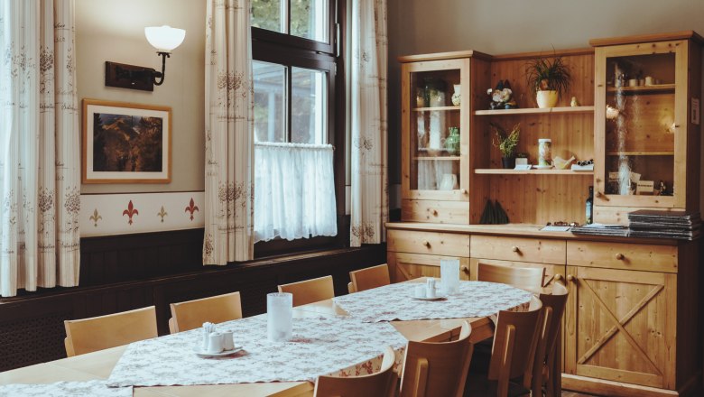 Cozy dining room with wooden furniture and tablecloths.