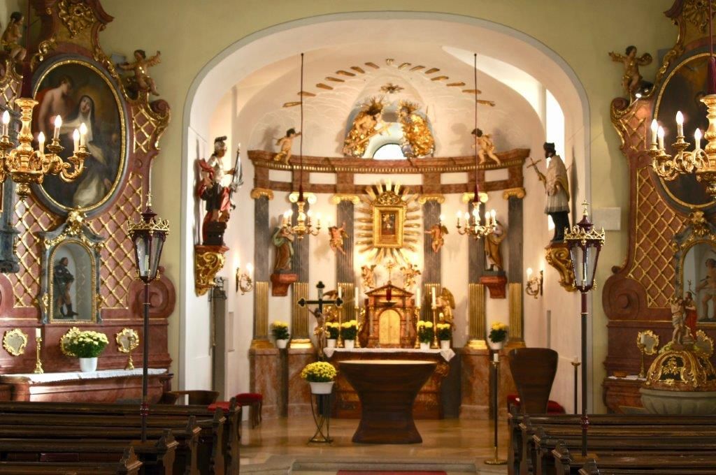 Interior of a richly decorated church with altar and statues.