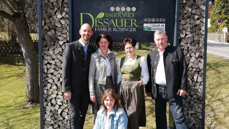 Five people in front of a sign with the inscription 'Bauernhof Dissauer Familie Rosinger'.