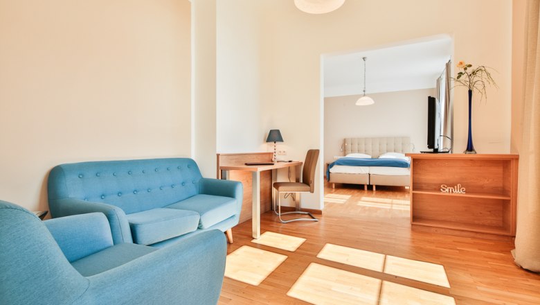Bright hotel room with blue furniture and double bed.
