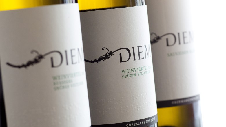 Close-up of Diem wine bottles with labels for Gr&uuml;ne Veltliner and Sauvignon Blanc.