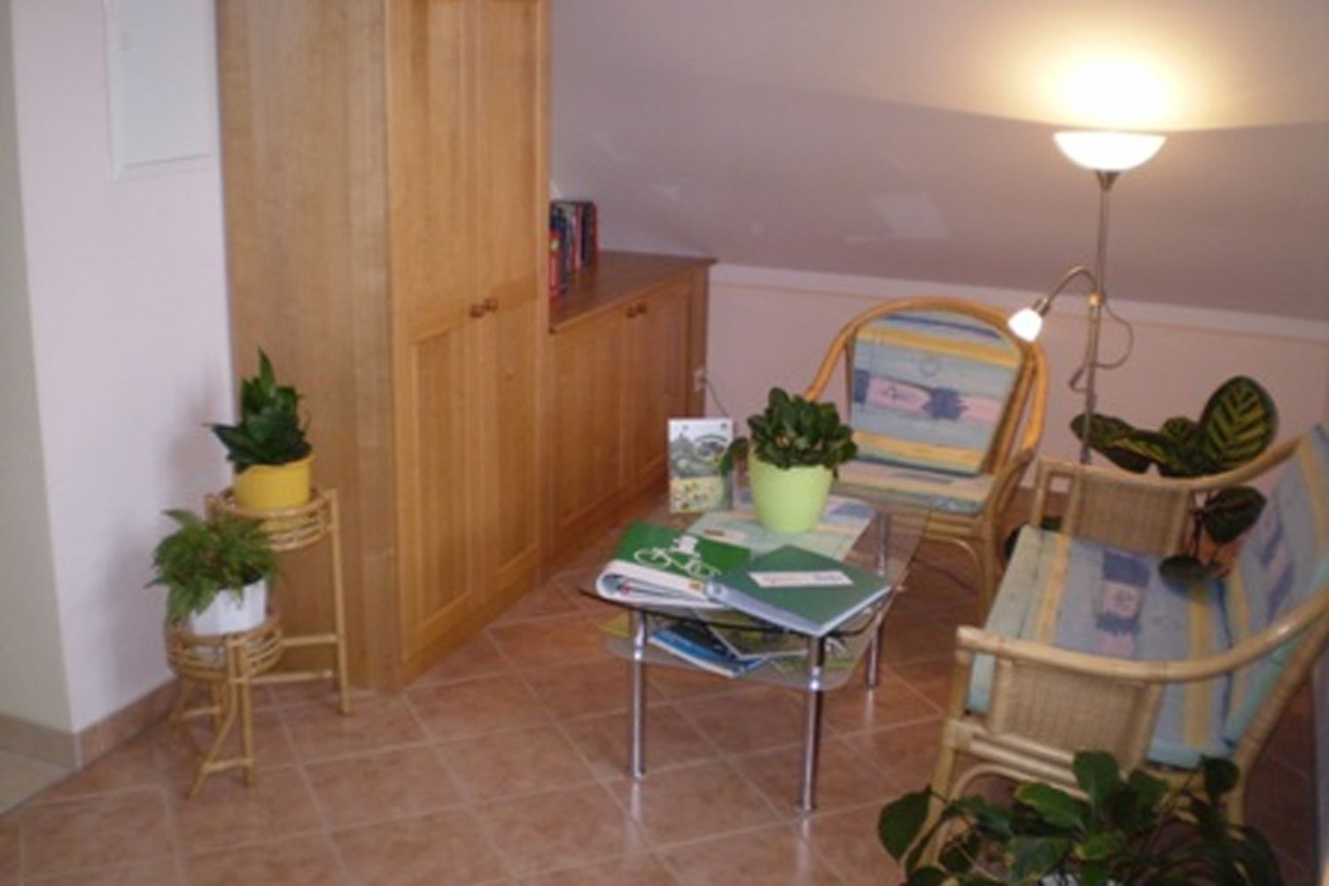 Cozy reading corner with rattan furniture, plants and a small table with books.