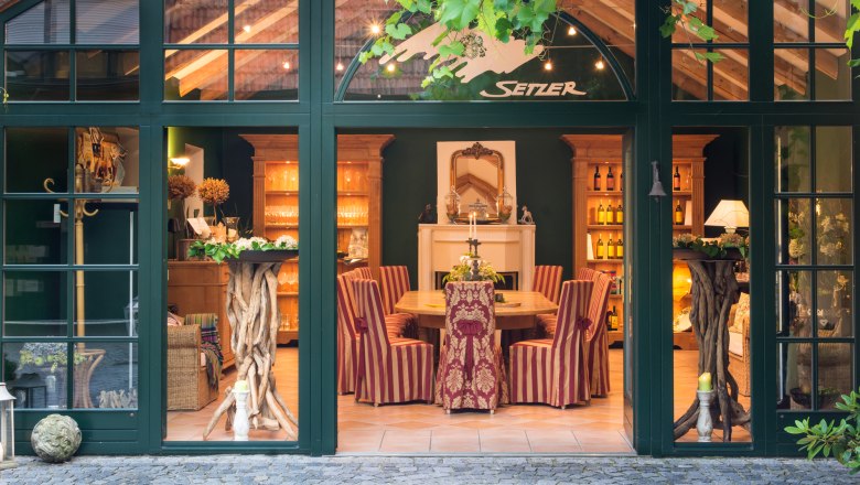 An elegant tasting room with wooden furniture, striped chairs and decorative elements. The room is visible through large windows.