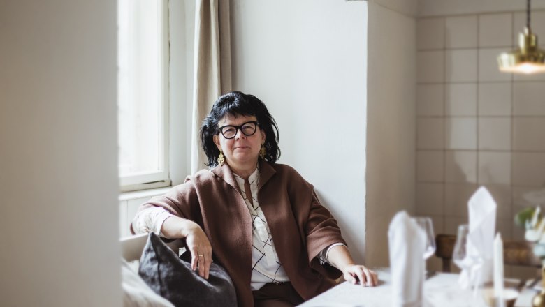 Woman sitting at a laid table in a cozy room.