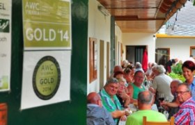 People sit at a long table in a covered outdoor area of a restaurant.