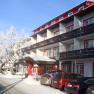 Winter hotel with snow-covered trees and parked cars.