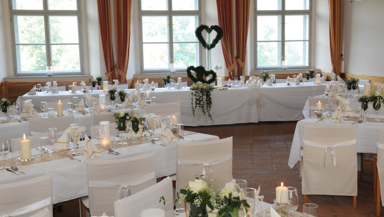 Elegant ballroom with laid tables, white chair covers and candles.