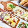 Various cold cuts and cheese platters with bread and salad on a table.