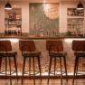 Interior view of a stylish bar with wooden chairs and illuminated counter.
