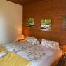 Cozy double room with wooden walls, a double bed with floral bedding and yellow blankets, as well as a bedside lamp.
