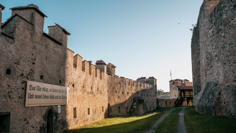 Inner corridor of the Kirchschlag castle ruins with old stone walls and a sign with an inscription.