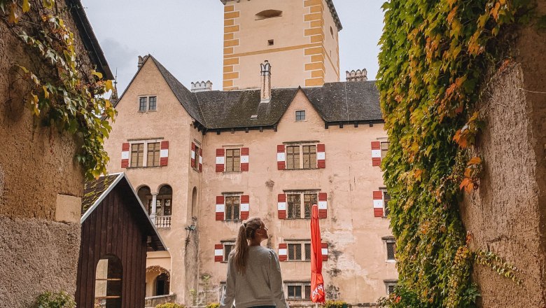 A person walks through an ivy-covered archway towards the inner courtyard of Ottenstein Castle.