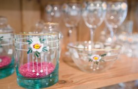 Glasses and bowls with floral motifs on a wooden shelf.