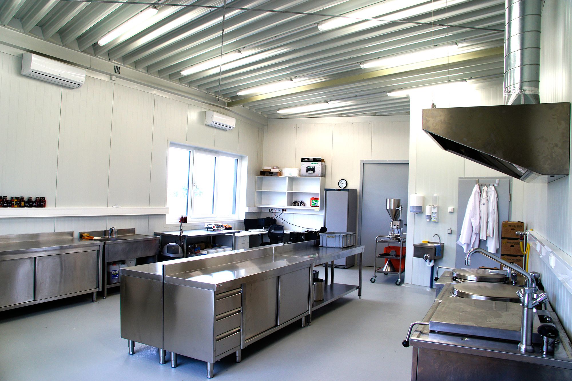 Modern industrial kitchen with stainless steel furniture and appliances.