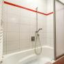 Bathroom with bathtub, shower head and red tiles.