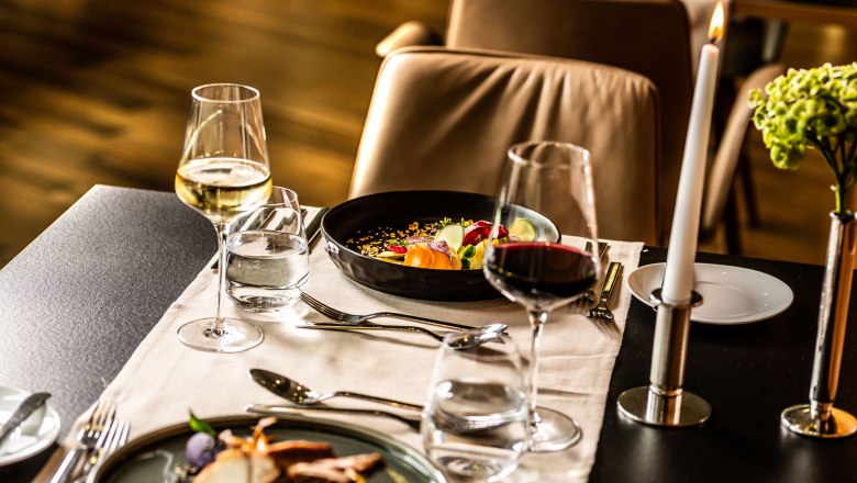 Elegant restaurant table with wine glasses, candle and gourmet dishes.