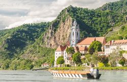 Eine Holzzille auf dem Wasser vor dem blauen Turm von Dürnstein.