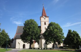 Pyhra parish church with tower and trees in the foreground.