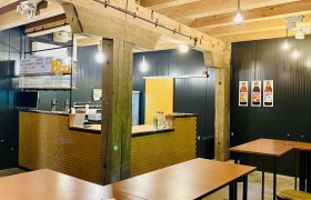 Interior view of a modern caf&eacute; with wooden beams, bar counter and high tables.