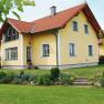 Yellow detached house with red roof and well-kept garden.