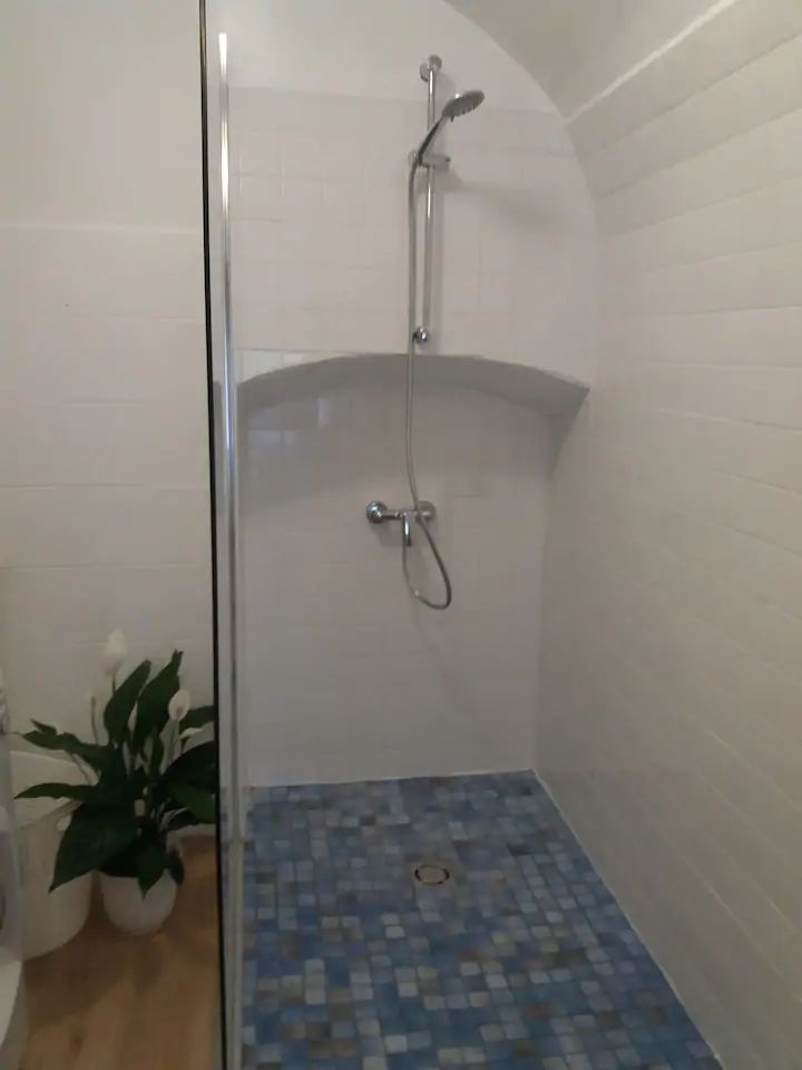 Modern shower with blue tiles and white walls.