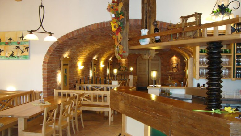 Innenansicht eines traditionellen Heurigen mit Holzmöbeln und Backsteinwänden.