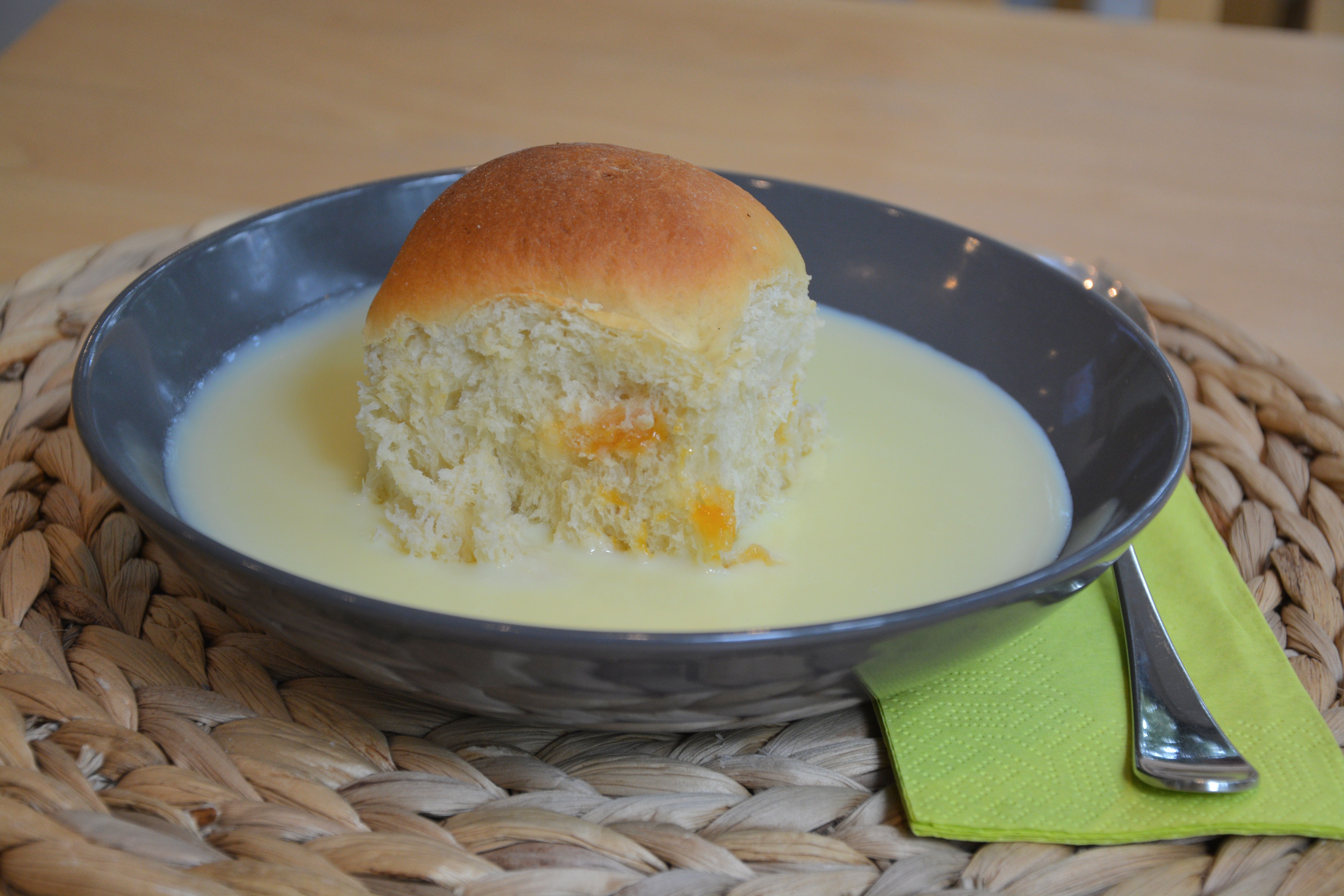 A black plate with a cake and vanilla sauce, next to it a green napkin with a fork.