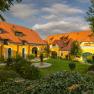 Yellow country estate with red roofs and well-tended garden.