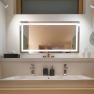 Modern washbasin with illuminated mirror, two taps, soap dispenser and hairdryer.