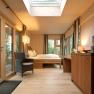 Interior view of a cozy tree house lodge with wooden furniture, bed, armchair and large skylight.