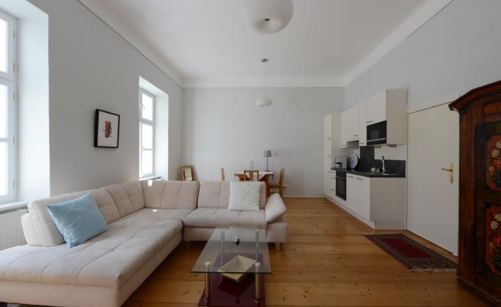 Bright living room with corner sofa, glass table, dining table and kitchenette.