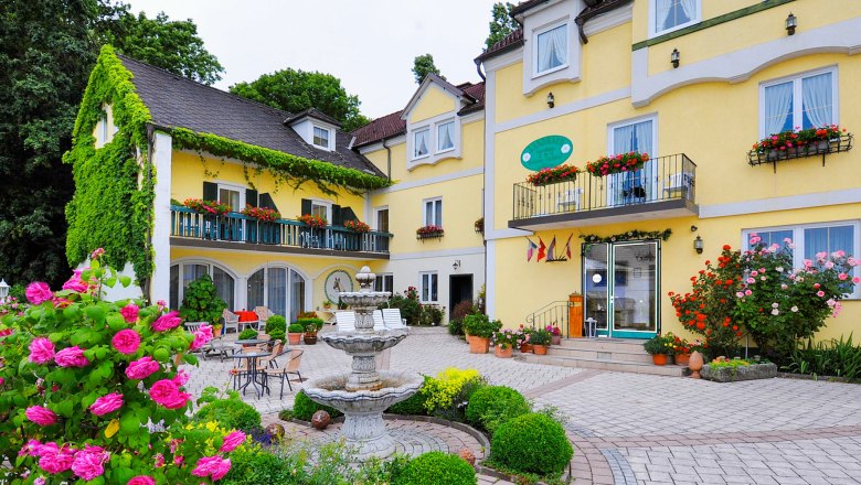 Yellow hotel building with floral decorations and fountain in the foreground.