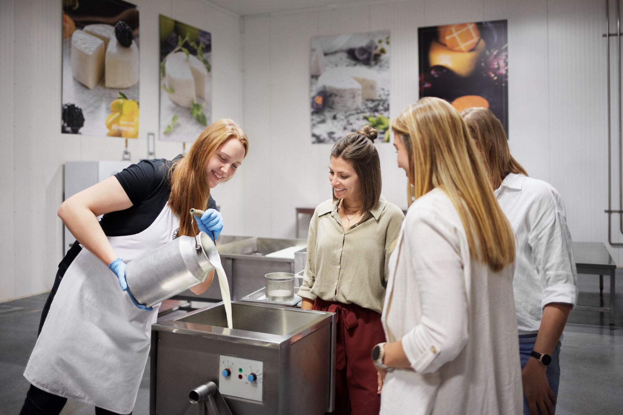 A woman pours milk into a container while three people look on.