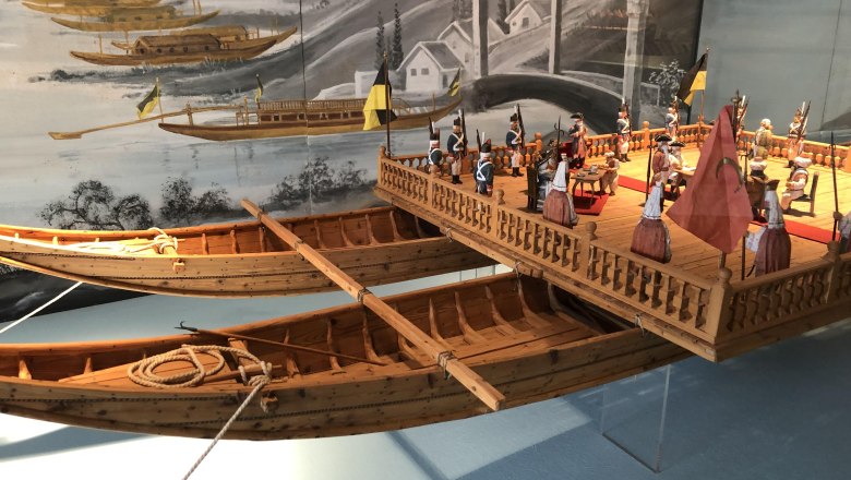 Model of a historic ship with figures in a museum.