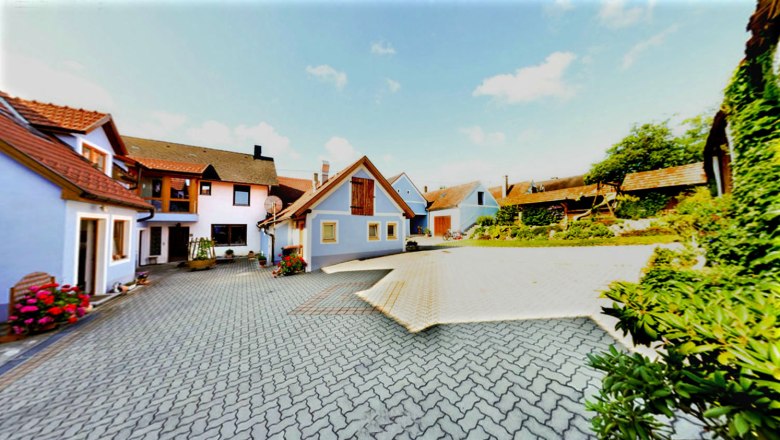 Winery - Guest rooms Hofbauer family, © Fam. Hofbauer Courtyard with several buildings, blue sky, paved ground, flowers and plants.
