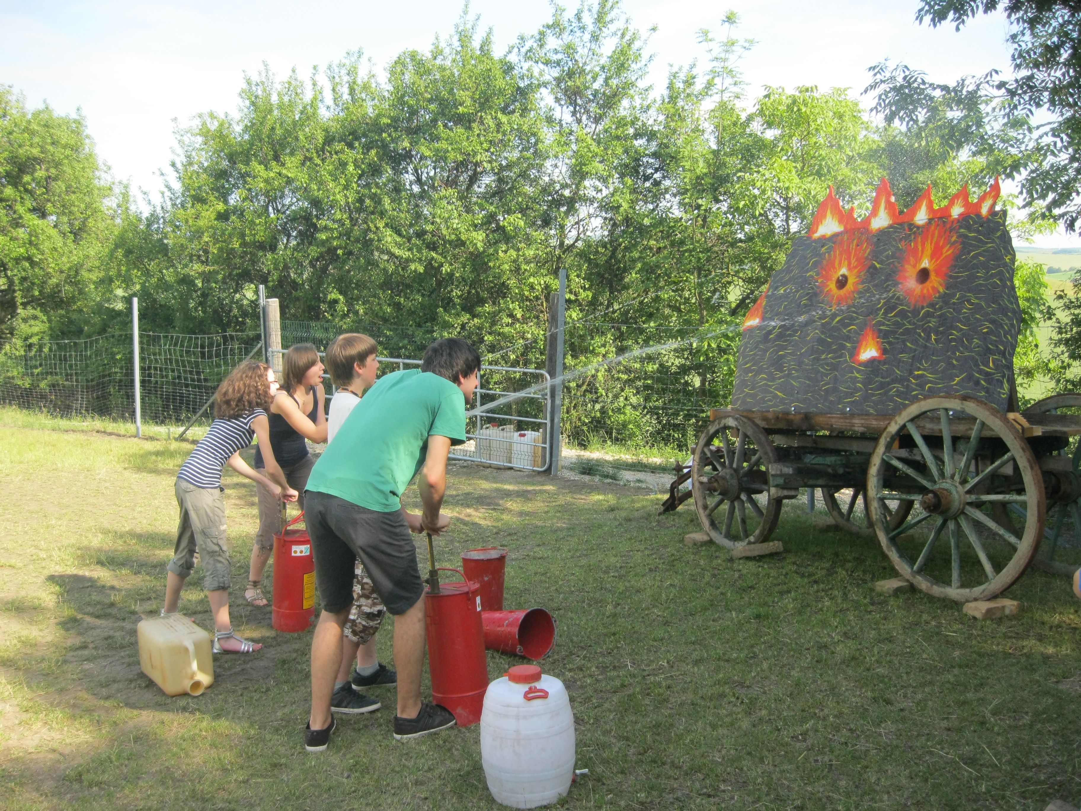 People extinguish a simulated fire on a wagon with water jets.