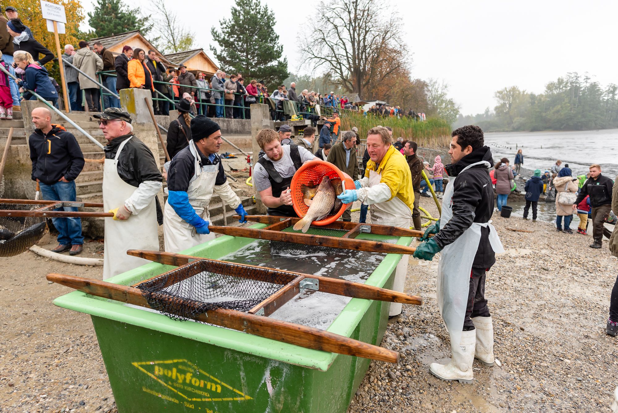 People at a fishing festival on a riverbank.