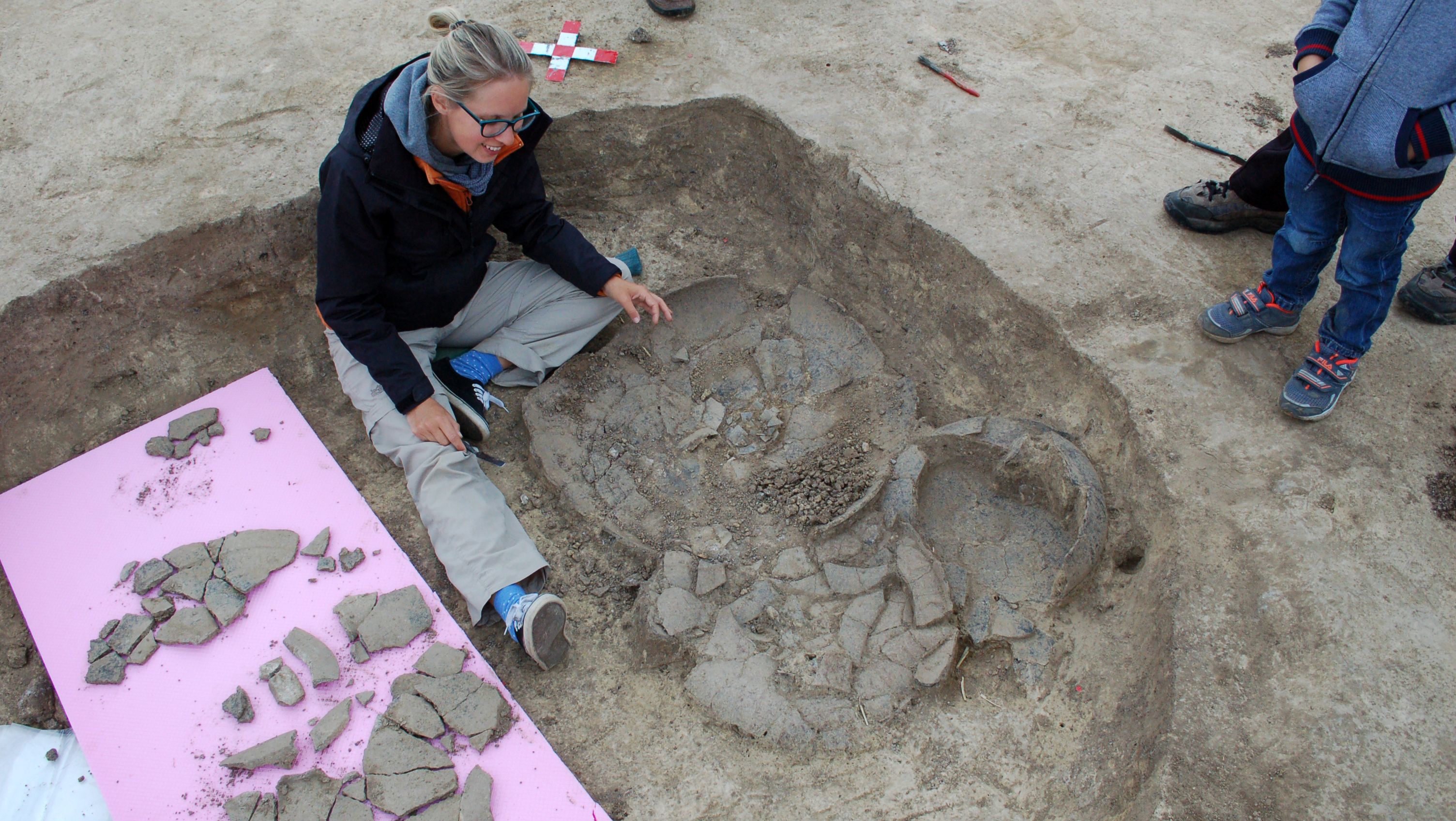 Archaeologist examines broken pottery at an excavation site.