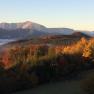 Autumn landscape with colorful trees and mountains in the background at sunrise.