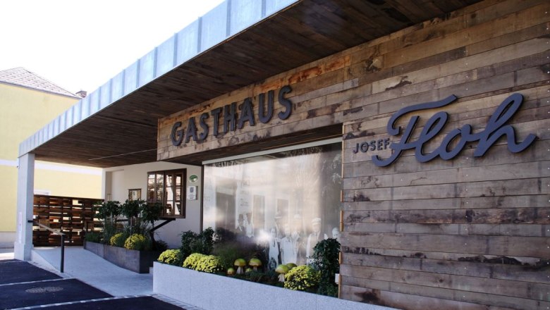 Exterior view of the Josef Floh guesthouse with wooden wall and plants.